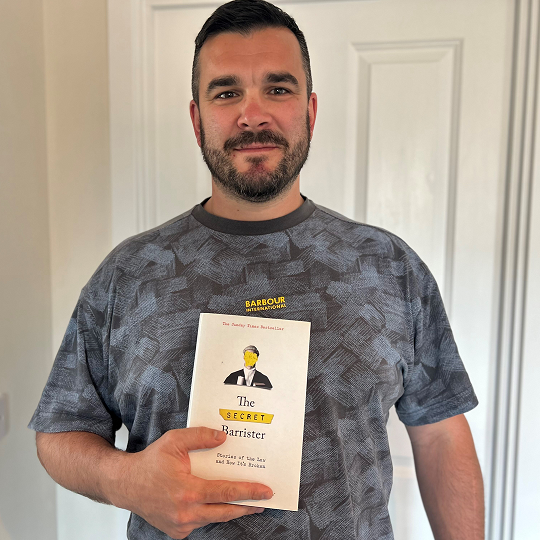 Tom, holding his book recommendation, The Secret Barrister